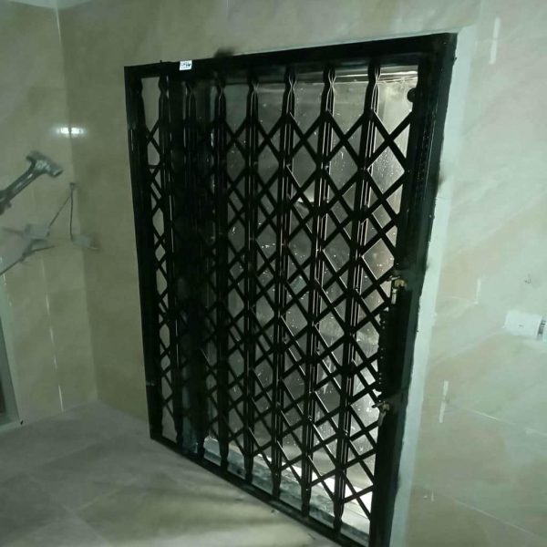 تصویر جمع‌شدن درب آکاردئونی ضد سرقت کنار دیوار